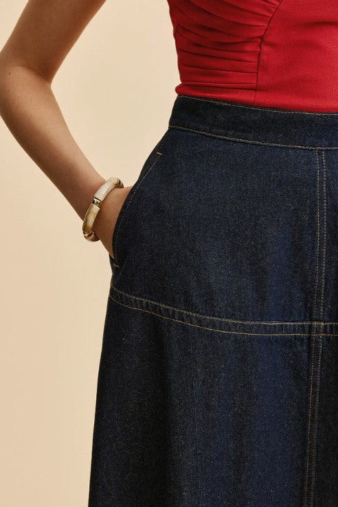 Person wearing a red top and blue denim skirt on a beige background