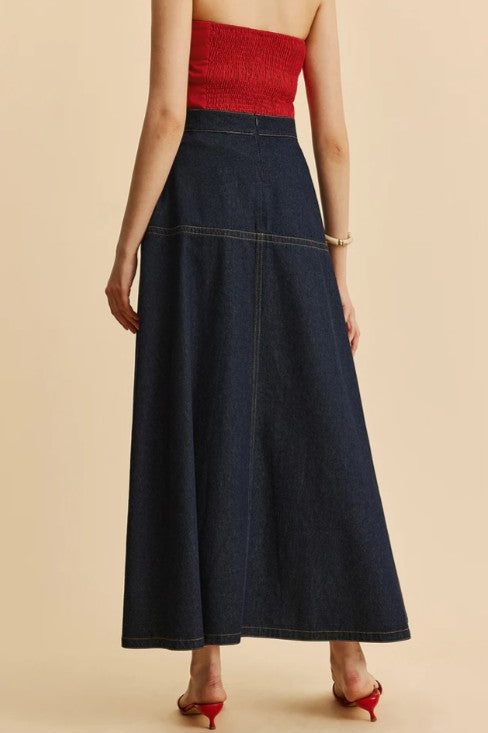 Woman wearing a red top and dark denim skirt on a beige background