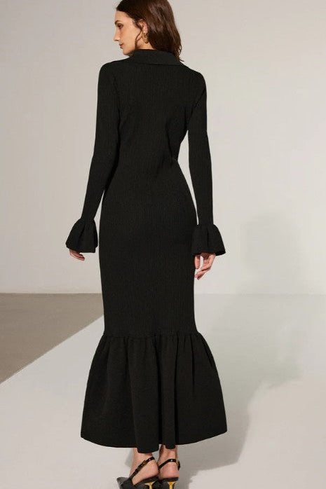 Black dress with long sleeves and a flared skirt on a plain background