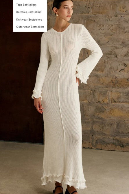 Woman wearing a long white dress against a stone wall.