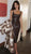 Woman in a brown leather dress holding a fur coat indoors.