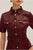 Maroon leather dress with gold buttons on a neutral background