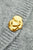 Gold brooch on a textured gray fabric background