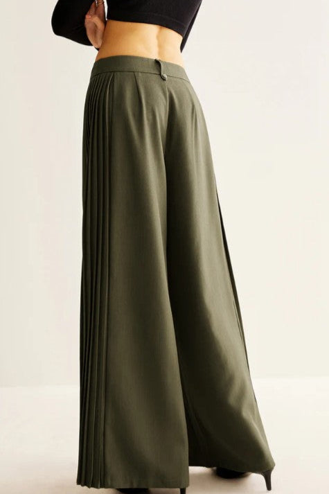 Green wide-leg pants worn by a person on a light background