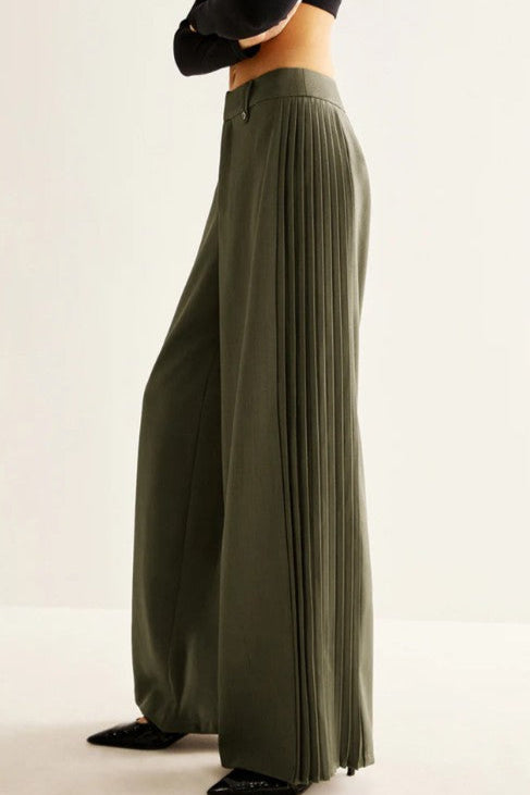 Green pleated skirt worn by a person on a plain background