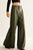 Green pleated pants worn by a person on a plain background
