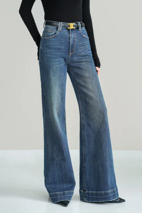 Blue flared jeans worn by a person on a light gray background